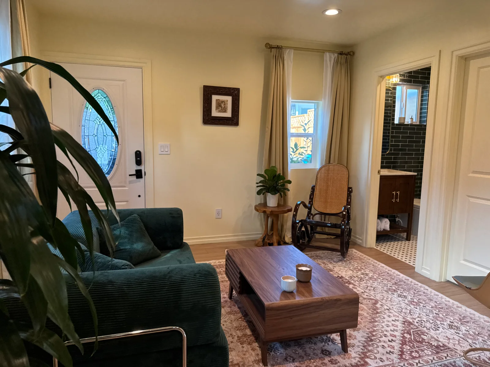 A living room with a green sofa, wooden coffee table, rug, and plants