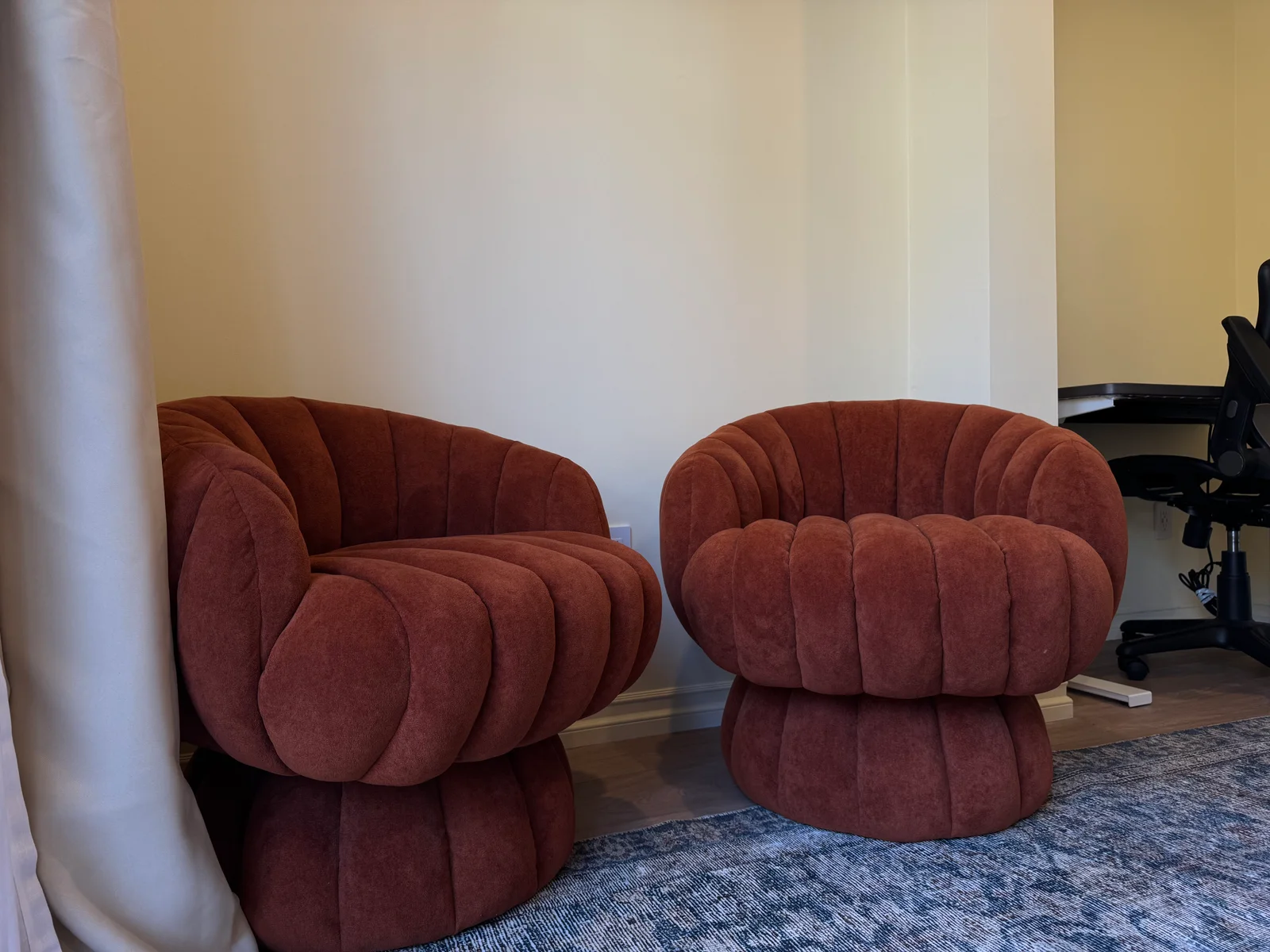 Two rounded rust-colored chairs on a patterned rug